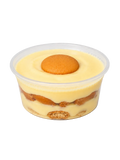 Banana pudding dessert in a clear container with layers of cream and cookies on a light gray background